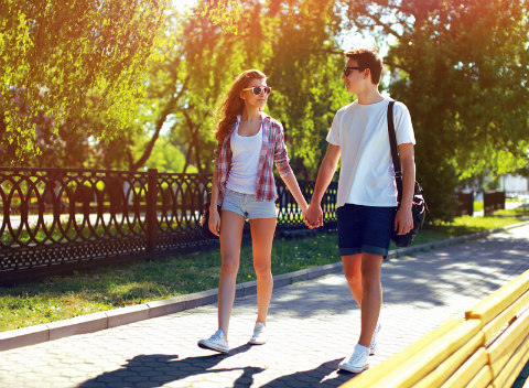 Young couple holding hands walking outdoors.