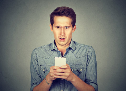 man horrified looking at his phone