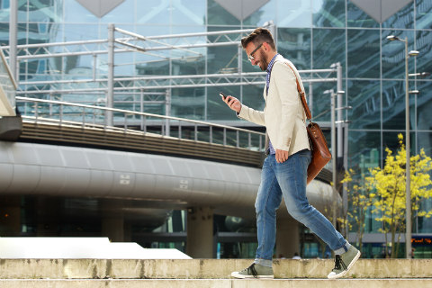 man walking smiling looking at phone in urban area